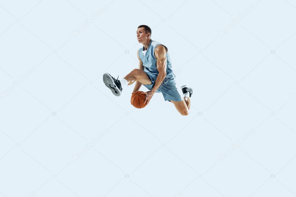 Young caucasian basketball player against white studio background