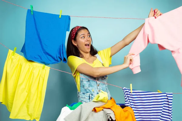 Engraçado e bela dona de casa fazendo tarefas domésticas no fundo azul — Fotografia de Stock