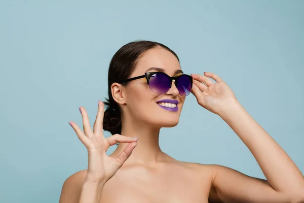 Portret van mooie jonge vrouw met heldere make-up geïsoleerd op blauwe studio achtergrond — Stockfoto