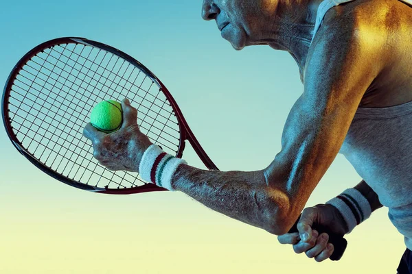 Homem sênior jogando tênis em sportwear no fundo gradiente e luz de néon — Fotografia de Stock