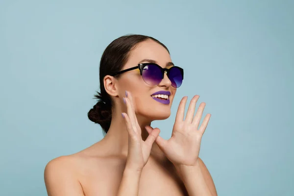 Portret van mooie jonge vrouw met heldere make-up geïsoleerd op blauwe studio achtergrond — Stockfoto