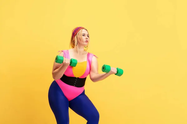 若い白人プラス黄色の背景に女性モデルのトレーニング — ストック写真