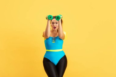 Genç beyaz, artı boyut kadın modeller sarı arka planda eğitim görüyor.