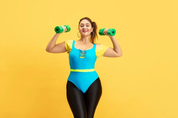 Jeune caucasien plus la taille des modèles féminins formation sur fond jaune — Photo