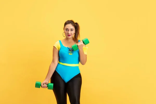 Jeune caucasien plus la taille des modèles féminins formation sur fond jaune — Photo