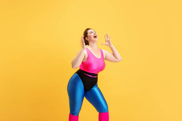 Young caucasian plus size female models training on yellow background
