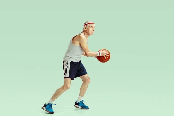 Senior-Mann spielt Basketball in Sportbekleidung isoliert auf grünem Hintergrund — Stockfoto