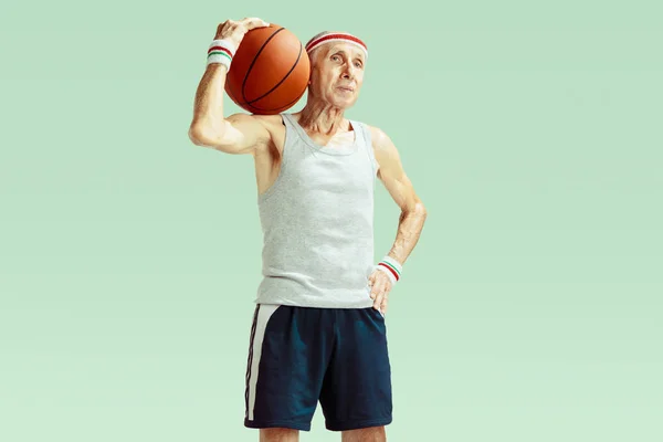 Senior man playing basketball in sportwear isolated on green background — Stock Photo, Image