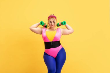 Genç beyaz, artı boyut kadın modeller sarı arka planda eğitim görüyor.