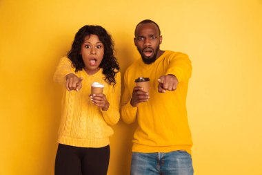 Sarı arka planda genç duygusal Afro-Amerikan erkek ve kadın