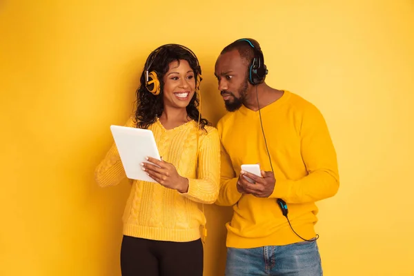 Jeune homme et femme afro-américain émotionnel sur fond jaune — Photo