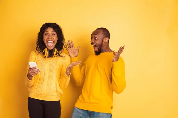 Jeune homme et femme afro-américain émotionnel sur fond jaune — Photo