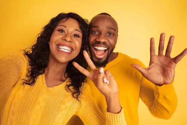 Mladý emocionální afroameričan muž a žena na žlutém pozadí — Stock fotografie
