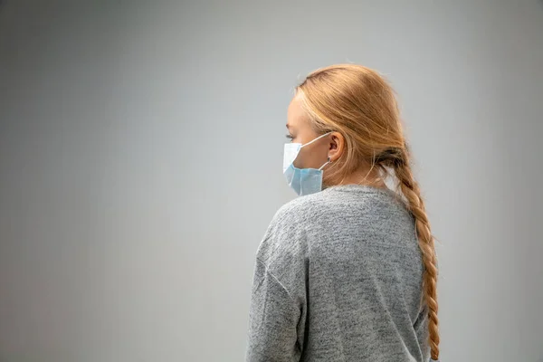 Chica caucásica con la máscara de protección respiratoria contra la contaminación del aire y el atardecer sobre fondo gris estudio — Foto de Stock