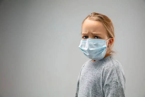 Menina caucasiana vestindo a máscara de proteção respiratória contra a poluição do ar e crepúsculo em fundo estúdio cinza — Fotografia de Stock