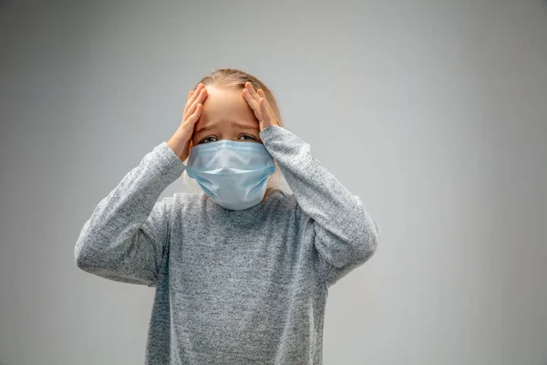 Caucasian girl wearing the respiratory protection mask against air pollution and dusk on grey studio background — Stock Photo, Image