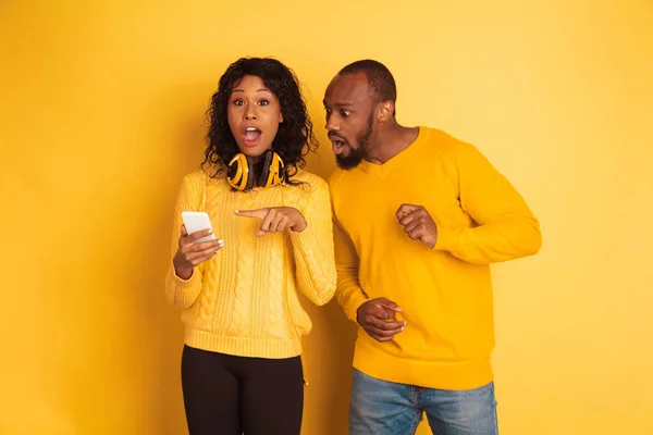 Jeune homme et femme afro-américain émotionnel sur fond jaune — Photo