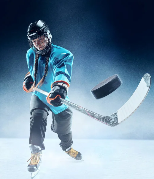 Joven jugadora de hockey con el palo en la pista de hielo y fondo azul — Foto de Stock