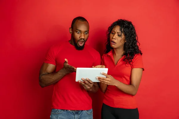 Fiatal érzelmi afro-amerikai férfi és nő a piros háttér — Stock Fotó