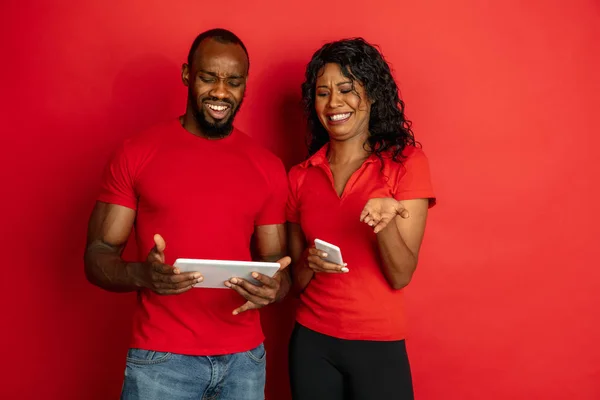 Ung känslomässig afrikansk-amerikansk man och kvinna på röd bakgrund — Stockfoto