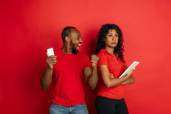 Jeune homme et femme afro-américain émotionnel sur fond rouge — Photo