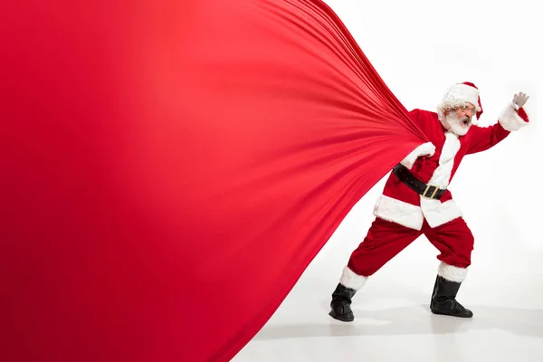 Noel Baba, Noel hediyeleriyle dolu koca çantayı çekiyor. Beyaz arka planda izole edilmiş. — Stok fotoğraf