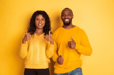 Sarı arka planda genç duygusal Afro-Amerikan erkek ve kadın