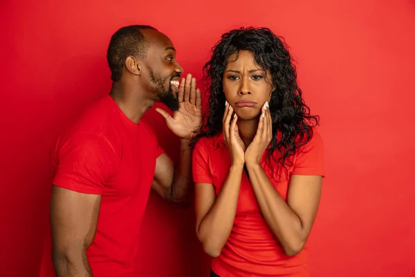 Młody, emocjonalnie afrykańsko-amerykański mężczyzna i kobieta na czerwonym tle — Zdjęcie stockowe