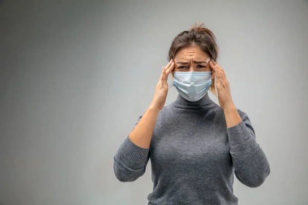 Mujer caucásica que usa la máscara de protección respiratoria contra la contaminación del aire y el atardecer en el fondo gris del estudio — Foto de Stock