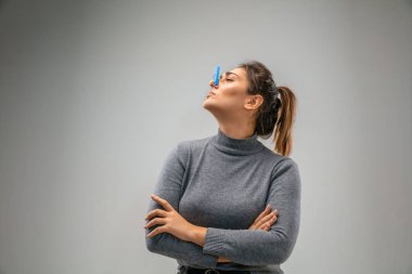 Solunum koruyucu iğne tokası takan beyaz kadın hava kirliliğine karşı ve gri stüdyo arka planında alacakaranlığa karşı