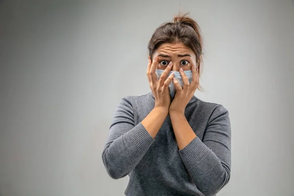 Donna caucasica indossa la maschera di protezione respiratoria contro l'inquinamento atmosferico e crepuscolo su sfondo grigio studio — Foto Stock