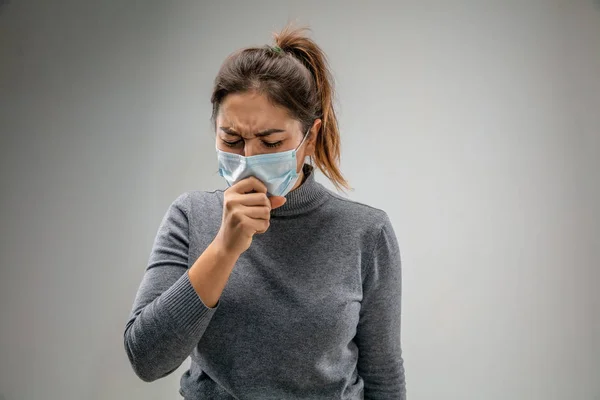 Mulher branca usando a máscara de proteção respiratória contra a poluição do ar e crepúsculo em fundo estúdio cinza — Fotografia de Stock