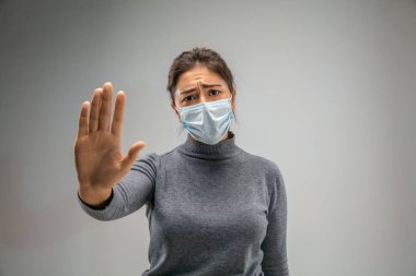 Solunum maskesi takan beyaz kadın hava kirliliğine karşı ve gri stüdyo arka planında alacakaranlığa karşı