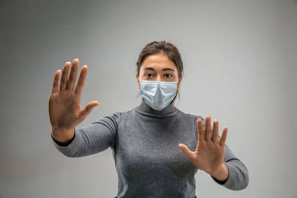 Mujer caucásica que usa la máscara de protección respiratoria contra la contaminación del aire y el atardecer en el fondo gris del estudio — Foto de Stock