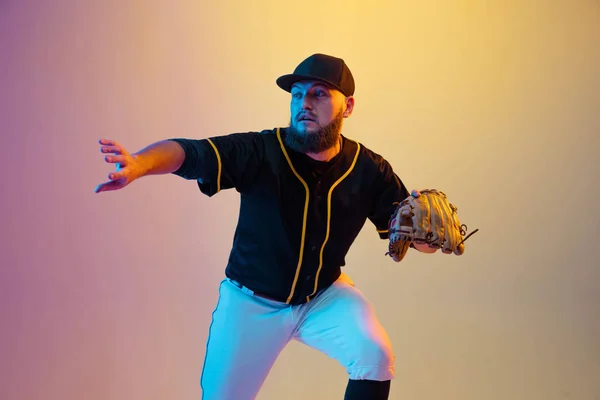 Baseball spelare, kastare i svart uniform öva på lutning bakgrund i neon ljus — Stockfoto