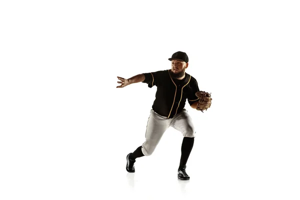 Jogador de beisebol, arremessador de uniforme preto praticando em um fundo branco . — Fotografia de Stock