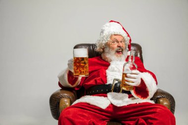 Noel Baba bira içiyor koltukta oturuyor, 2020 yılını kutluyor.