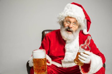 Noel Baba bira içiyor koltukta oturuyor, 2020 yılını kutluyor.