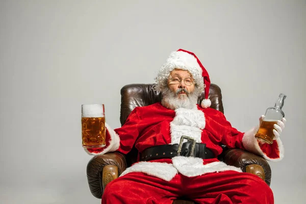 Santa Claus drinking beer sitting on armchair, congratulating of New Year 2020 — Stock Photo, Image