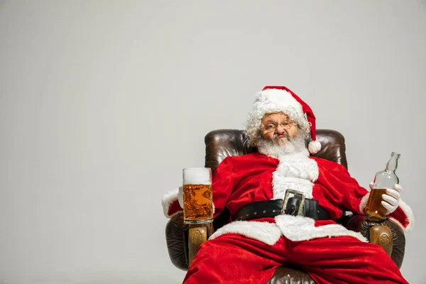 Santa Claus bebiendo cerveza sentado en el sillón, felicitando de Año Nuevo 2020 — Foto de Stock