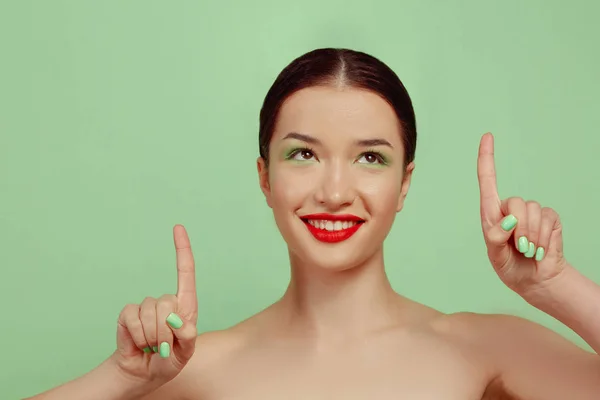 Portrait de belle jeune femme avec un maquillage lumineux isolé sur fond de studio vert — Photo