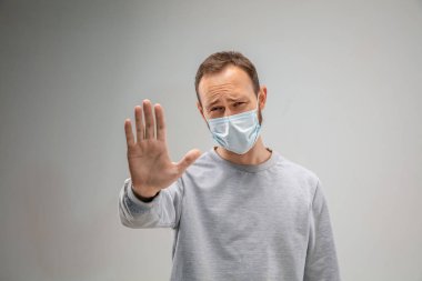 Solunum maskesi takan beyaz bir adam hava kirliliğine karşı ve gri stüdyo arka planında alacakaranlığa karşı