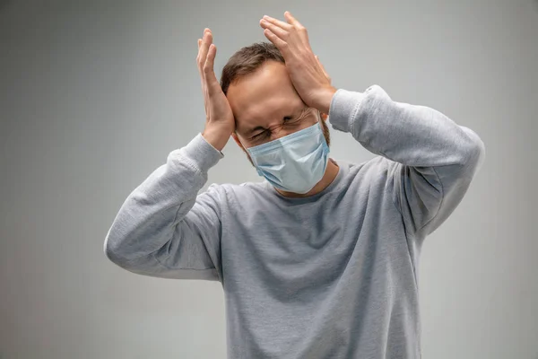 Solunum maskesi takan beyaz bir adam hava kirliliğine karşı ve gri stüdyo arka planında alacakaranlığa karşı — Stok fotoğraf
