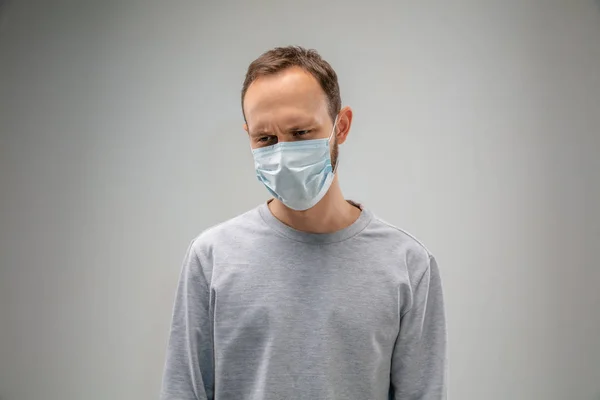 Кавказький чоловік, одягнений у протидихальну маску для захисту від забруднення повітря і сутінки на сірому фоні студії — стокове фото