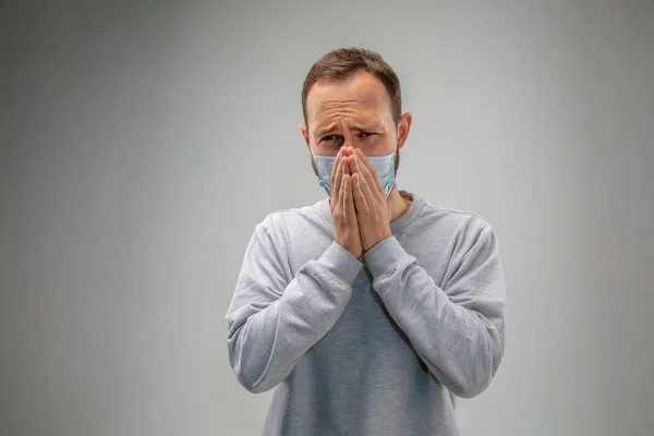 Белый мужчина в маске защиты дыхательных путей от загрязнения воздуха и сумерках на фоне серой студии — стоковое фото