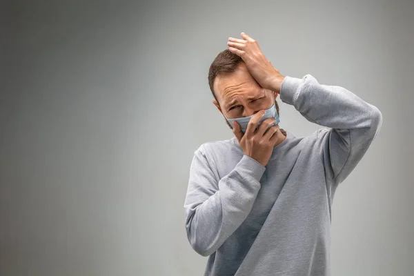 Hombre caucásico usando la máscara de protección respiratoria contra la contaminación del aire y el atardecer en el fondo gris del estudio — Foto de Stock
