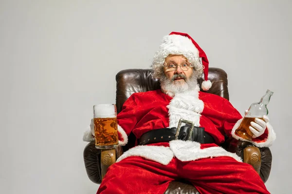 Άγιος Βασίλης πίνοντας μπύρα κάθεται στην πολυθρόνα, συγχαίροντας της Πρωτοχρονιάς 2020 — Φωτογραφία Αρχείου