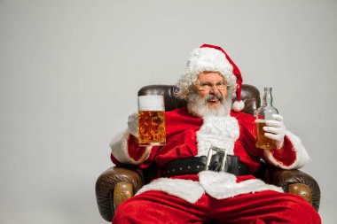 Noel Baba bira içiyor koltukta oturuyor, 2020 yılını kutluyor.