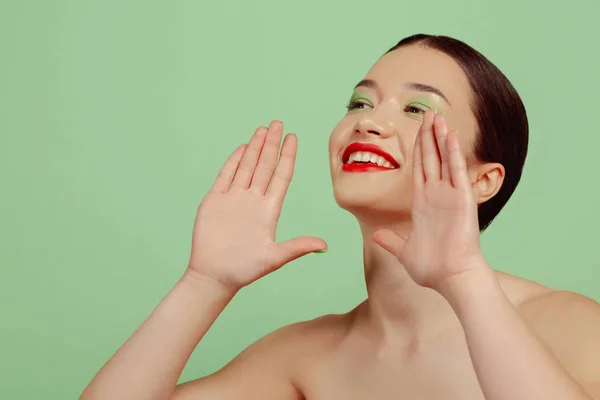 Portret van mooie jonge vrouw met heldere make-up geïsoleerd op groene studio achtergrond — Stockfoto