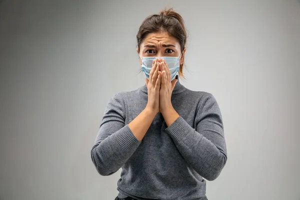 Mujer caucásica que usa la máscara de protección respiratoria contra la contaminación del aire y el atardecer en el fondo gris del estudio — Foto de Stock